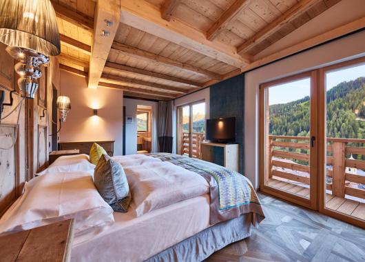 Schlafzimmer mit Fernseher und Terrasse - Suite Dolomites Mountain Spa