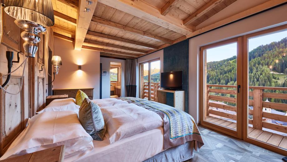 Schlafzimmer mit Fernseher und Terrasse - Suite Dolomites Mountain Spa