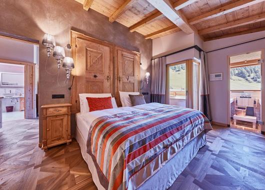 Schlafzimmer mit Doppelbett und Holzboden - Suite Dolomites Mountain Spa