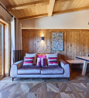 Soggiorno in stile ladino con pavimento in legno e terrazza - Suite Dolomites Mountain Spa
