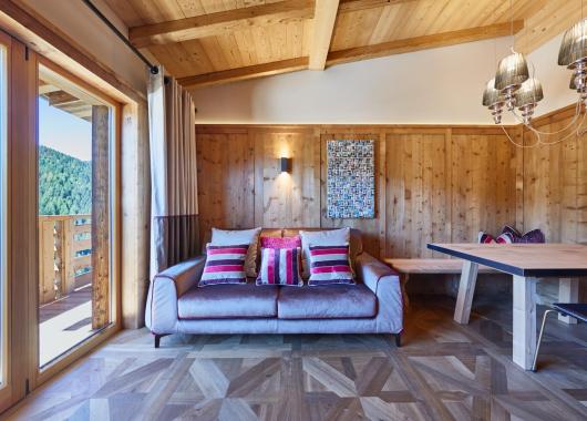 Soggiorno in stile ladino con pavimento in legno e terrazza - Suite Dolomites Mountain Spa