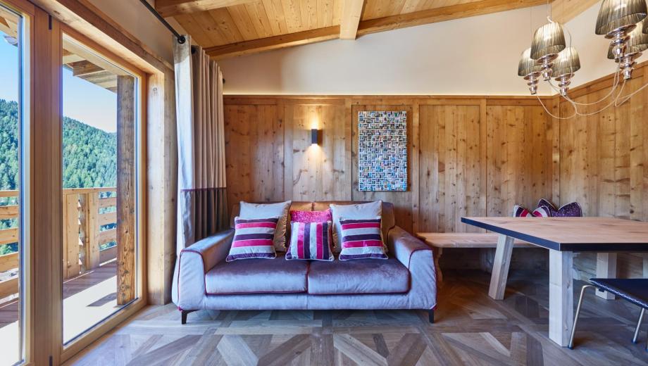 Soggiorno in stile ladino con pavimento in legno e terrazza - Suite Dolomites Mountain Spa